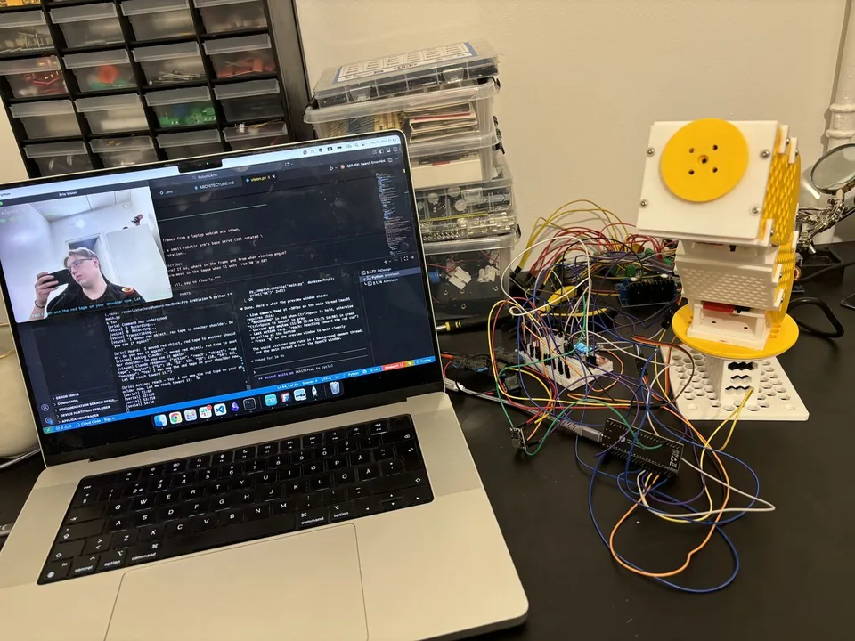 Workspace shot — laptop running the vision script, the arm to the right with cabling and breadboards