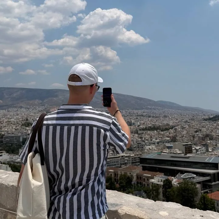 Roman holding up a phone above Athens